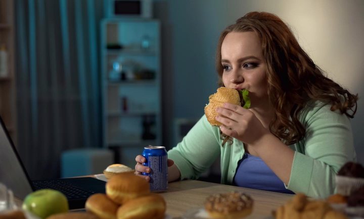 Eine übergewichtige Frau am Überessen mit Fast Food