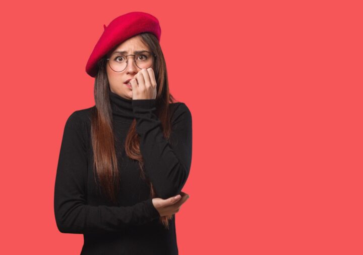 Eine nervöse Frau, die an ihren Fingernägeln beißt