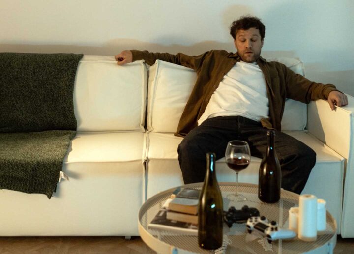 Ein betrunkener Mann auf der Couch in seinem Wohnzimmer