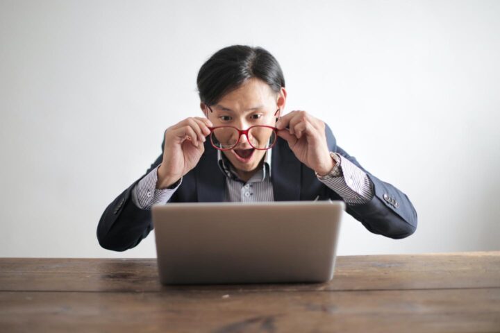 Ein Mann mit erschrockener Miene, der Nachrichten auf einer Website liest